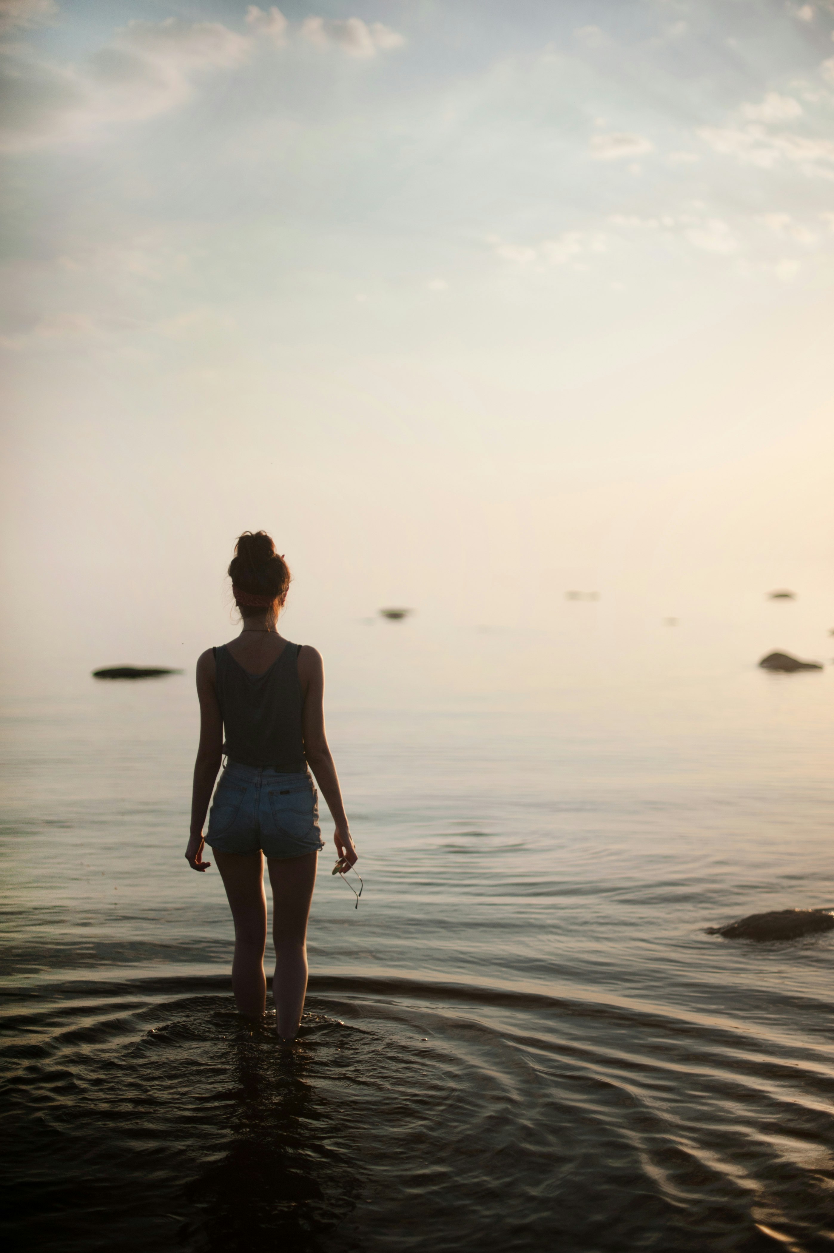 woman in black tank top and white shorts walking on beach during daytime